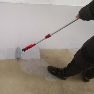 Une personne applique de la peinture blanche sur le sol de son garage