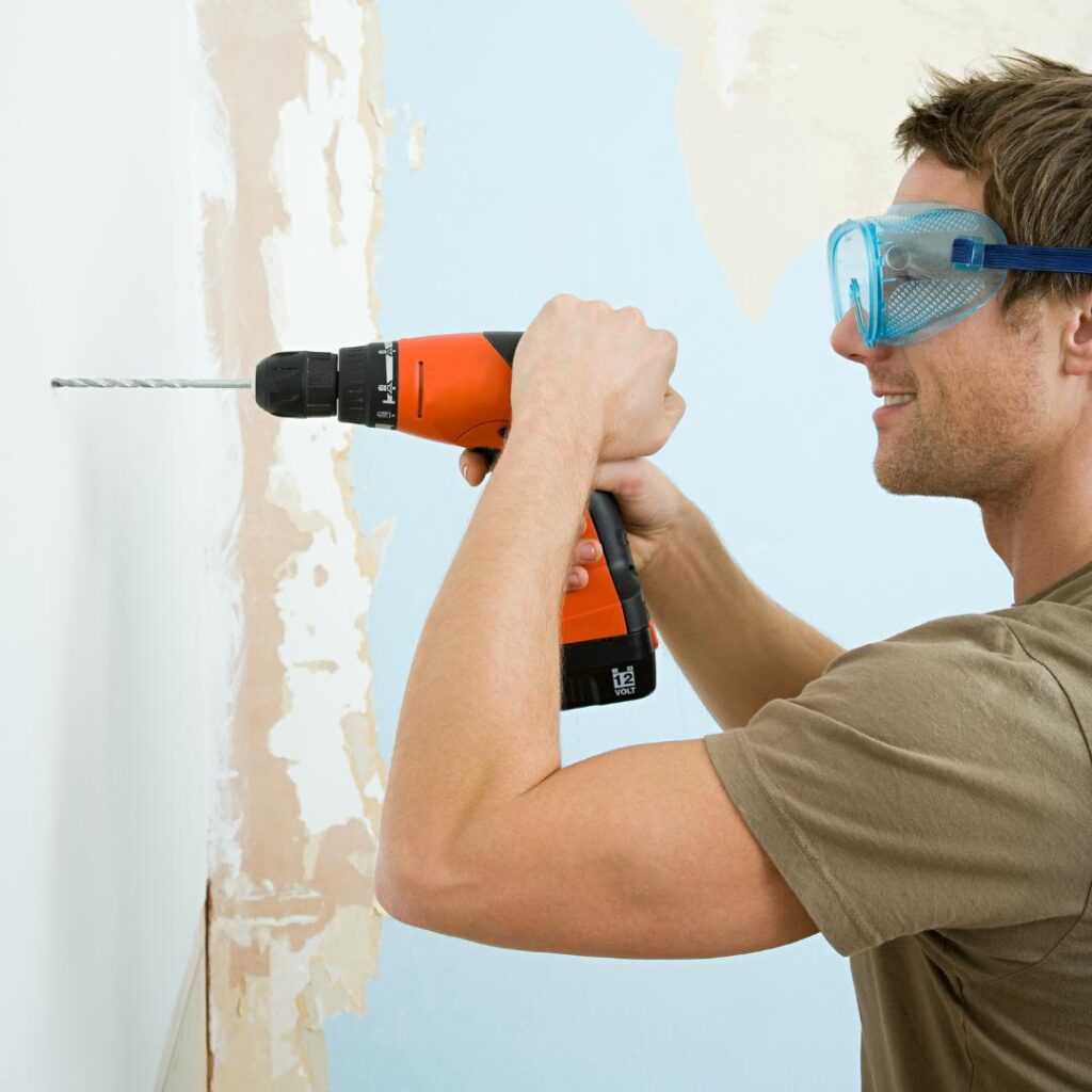 Homme qui perce un mur en béton