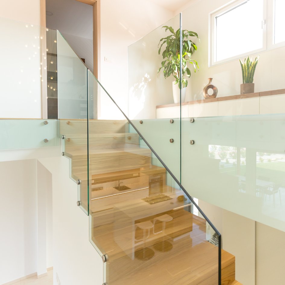 Escalier droit en bois clair avec une rampe vitrée