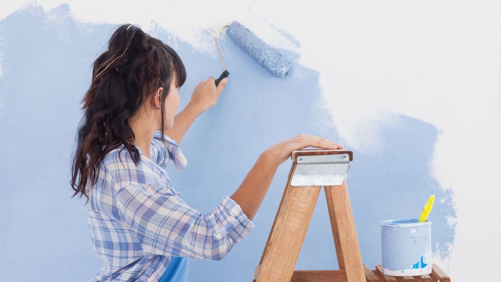 Femme qui peint un mur en bleu