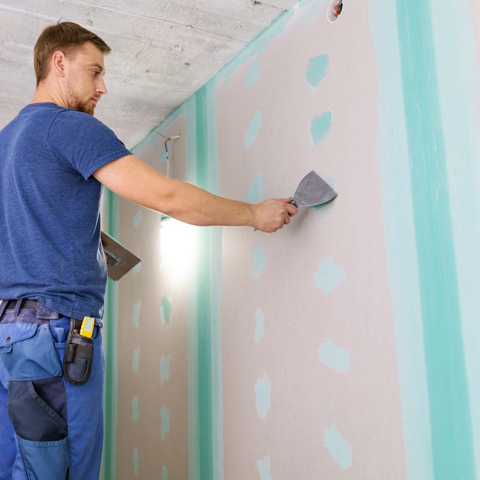 Homme qui enduit une plaque de plâtre