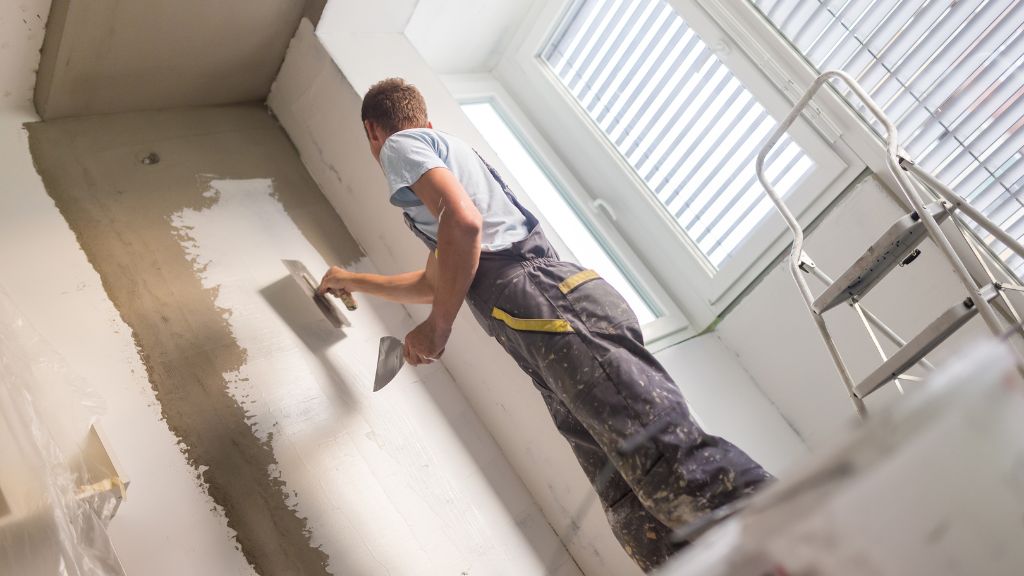 Homme qui rénove un mur avec de l'enduit