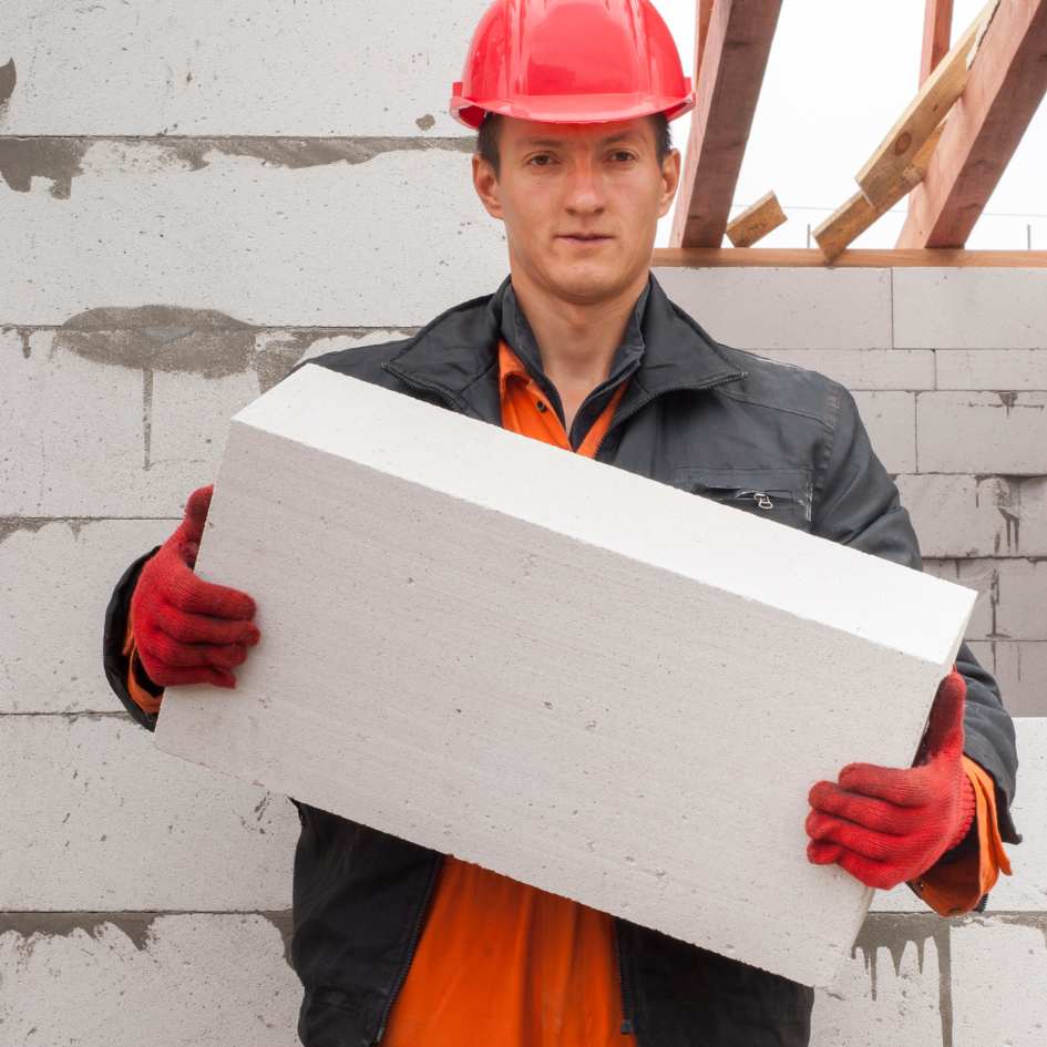 Homme qui porte du béton cellulaire