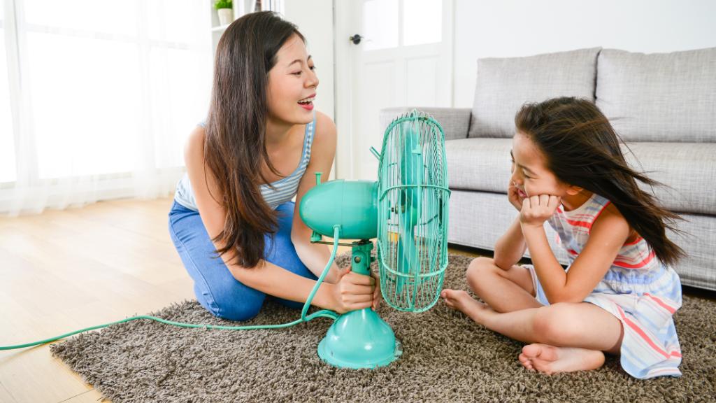 Une mère et une fille devant un ventilateur bleu