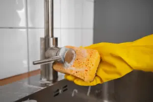 Personne qui nettoie son robinet d'évier à l'aide d'une éponge non-abrasive