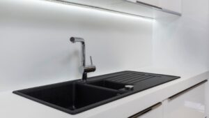 Cuisine blanche avec un évier de cuisine noir avec égouttoir 