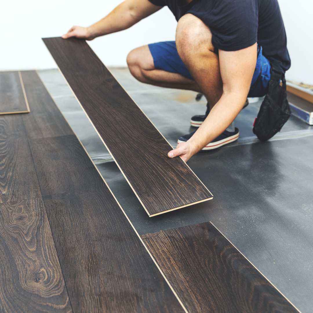 Homme qui installe du parquet stratifié