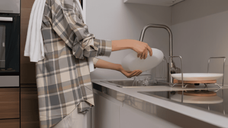 Une personne qui fait la vaisselle dans un petit évier de cuisine