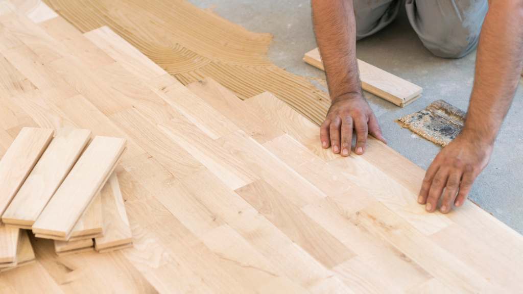 Homme qui colle un parquet clair